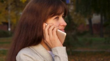 güzel kadın smartphone üzerinde söz ve park, mutlu kız gülümser gider. iş kadını elinde belgeler ile siyah bir evrak çantası taşıyor. yakın çekim