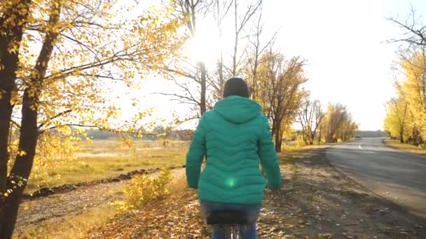 Ragazza in sella alla bicicletta sulla strada in autunno nel parco — Video Stock