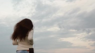 Spor kız saç geliştirme ile kulaklık mavi gökyüzüne karşı çalıştırmak bir akşam devreye girer