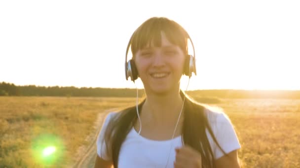 Menina bonita em fones de ouvido ouve música e vai para jogging esportes e sorrisos. Desporto como modo de vida — Vídeo de Stock