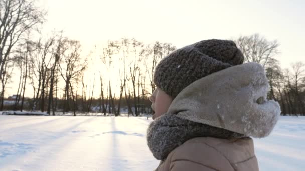 Teen girl getta neve bianca e sorride nel parco invernale. Natale. Giochi con la neve il giorno gelido — Video Stock