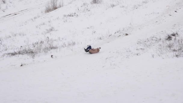 Meisje rollen van hoge besneeuwde berg op sneeuw schotel. Kerstmis. Games met sneeuw op frosty dag — Stockvideo