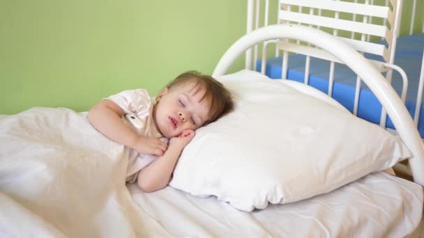 A criança dorme na enfermaria do hospital. conceito de criança adormecida. bebê encantador adormece na cama branca em sua cama  . — Vídeo de Stock