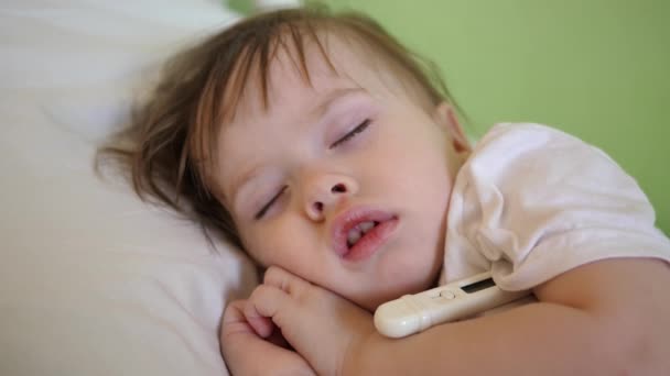 La temperatura del niño se mide con termómetro en la sala de hospitalización. Primer plano. Bebé duerme en el hospital en una cama blanca . — Vídeo de stock