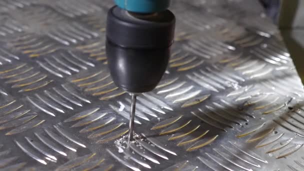 Borrning lysande metall med en elektrisk borr. arbetaren borrar hål i plåt av aluminium. reparationsarbeten i verkstaden. närbild — Stockvideo