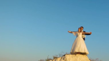 Sevgili gelin ve damat mavi gökyüzü karşı elele ve gülümseyerek. Balayı. Aile hayatı kavramı. Erkekler ve kadınlar arasında romantik ilişkiler.