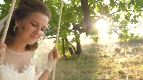 Belle mariée en robe blanche balançant sur balançoire dans parc sur une branche d'un chêne. gros plan — Video