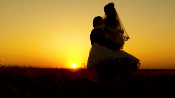 Silhouet van liefdevolle bruid en bruidegom gaan rond en rond en dansen tegen de achtergrond van de zonsondergang. Huwelijksreis. concept van het gezinsleven. romantische relatie van de man en een vrouw. — Stockvideo