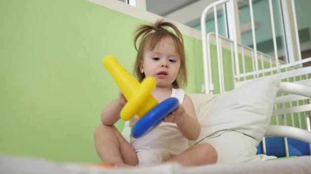 子供と赤ちゃんは、ピラミッドと色のリングが付いているベッドで再生します。保育園と幼稚園の子供の教育おもちゃ。女の子のためのおもちゃ. — ストック動画