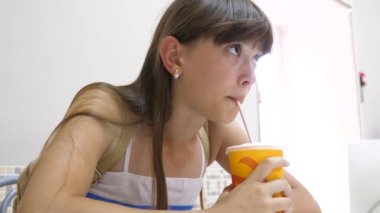 Güzel kız masada kafe ve içme kokteyl ve gülümseyerek oturuyor