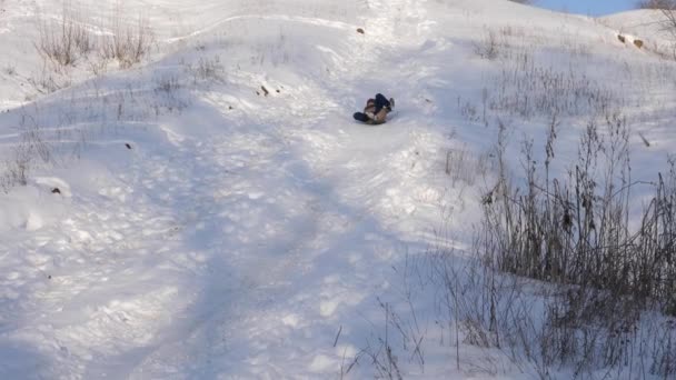 Ragazza felice rotola giù per la collina in slitta nella neve. ragazza che gioca in inverno nel parco di Natale. Rallentatore — Video Stock