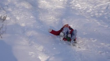 kız kar kızakta tepeden aşağı yuvarlanıyor. kız kış aylarında parkta oynuyor. Ağır çekim