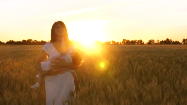 Matka drží malou dceru a dává ji do režimu spánku. Matka s dítětem hraje na večerní procházku v oblasti pšenice. Zpomalený pohyb — Stock video