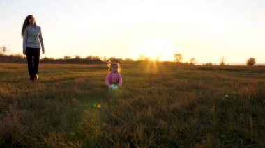 mutlu çocuk çimenlerin üzerinde atar futbol topu topu ile çalışır. Küçük çocukla çocuk top bir parkta oynarken günbatımında aile. Ağır çekim