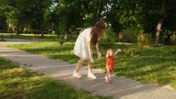 Перші кроки дитини з мамою. Мама грає зі своєю маленькою донькою в літньому парку. Мама і дитина на шляху . — стокове відео