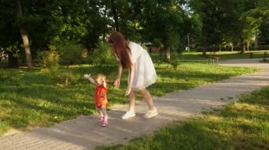 Anne küçük kızı yaz Park çalış. ilk adımları bebekle anne. Anne ve Çocuk yolda.