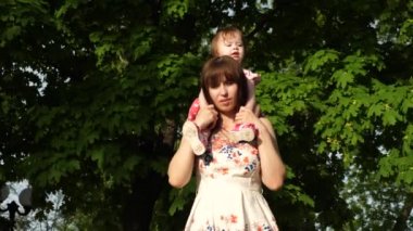 yürümek bir çocukla Park, Anne kızı onun omuzlarında taşır.