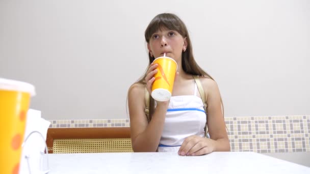 Menina bonita está sentada à mesa no café e beber coquetel e sorrindo — Vídeo de Stock