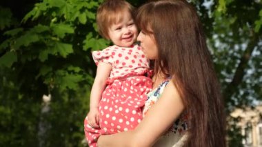 mutlu anne güzel bir kızın kucağında taşır, anne yaz Park'ta bir çocukla yürür