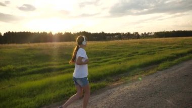 kız müzik kulaklık yol boyunca çalışır. güzel kız spor egzersizleri, ağır çekim yapıyor