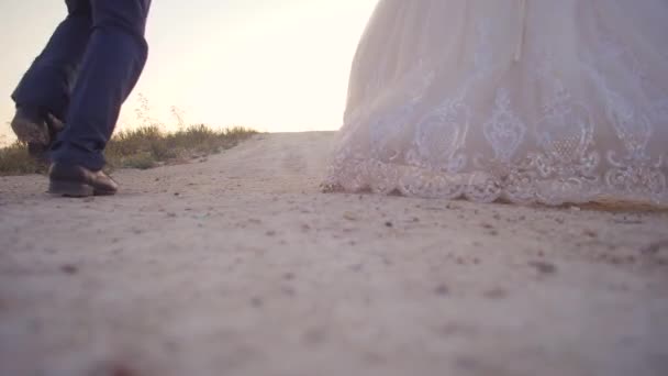 Bruid en bruidegom lopen langs de witte weg naar de hemel, slow-motion schieten — Stockvideo