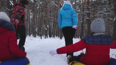 Kış ormandaki çocuklu mutlu baba ve anne çekme yıkılıyor. kışın karlı bir parkta çocuklu veliler oynayan. mutlu aile Noel tatili sırasında halletme