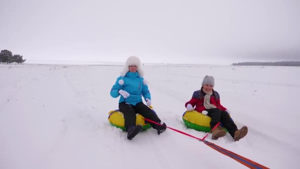 Feliz mamá niños patina en invierno en la nieve y jugar bolas de nieve. Mamá e hija se ríen y se regocijan. familia jugando en el parque de invierno durante las vacaciones de Navidad. Movimiento lento — Vídeos de Stock