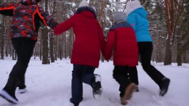 mutlu anne ve baba çocukları ile kış orman içinden çalıştırın. kışın karlı bir parkta çocuklu veliler oynayan. mutlu aile Noel Ormanda yürür.