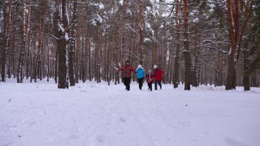 mutlu çocuk ve annem ve babam kış orman çocuklarda ile çalıştırın. kışın karlı bir parkta çocuklu veliler oynayan. mutlu aile Noel Ormanda yürür. takım çalışması