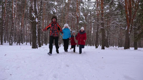 Šťastné děti a máma a táta s dětmi v zimním lese. rodiče s dětmi v zasněženém parku hrát v zimě. šťastná rodina procházky v lese vánoční. Týmová práce — Stock fotografie