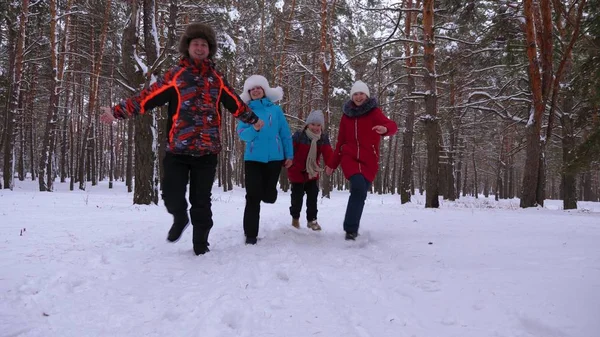 Crianças felizes e mamãe e papai correm com as crianças na floresta de inverno. os pais brincam com crianças em um parque nevado no inverno. família feliz caminha na floresta de Natal. trabalho em equipa — Fotografia de Stock