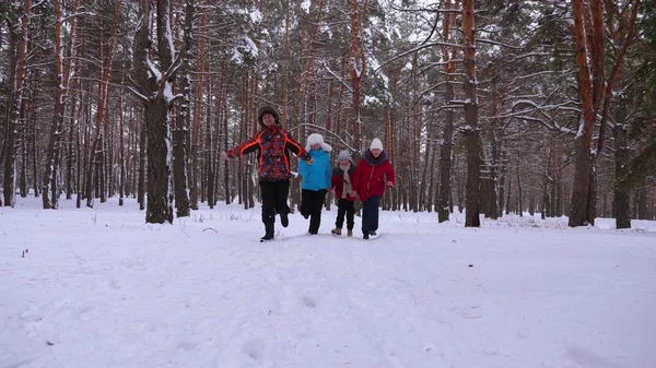 Glückliche Kinder und Mama und Papa laufen mit den Kindern im Winterwald. Eltern spielen im Winter mit Kindern in einem verschneiten Park. glückliche Familienspaziergänge im Weihnachtswald. Teamarbeit — Stockfoto