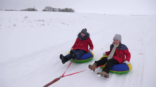 Bambini felici slittino in inverno sulla neve e agitando le mani. i bambini ridono e gioiscono. ragazza che gioca nel parco invernale per le vacanze di Natale — Foto Stock