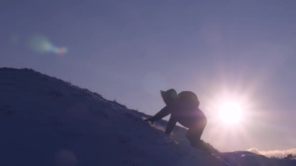 Klättrare klättrar snötäckta berg i strålar ljusa solen. turist gör klättra upp till toppen på bakgrund av vacker himmel. mannen flyttar upp till sin framgång. — Stockvideo