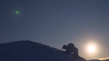 dağcı karlı dağ tırmanıyor, aşağı slaytlar ve daha parlak güneş ışınlarının yükselir. Turist onun başarı sevinir onun ellerini havaya kaldır ve mutlu atlama yükseltir.