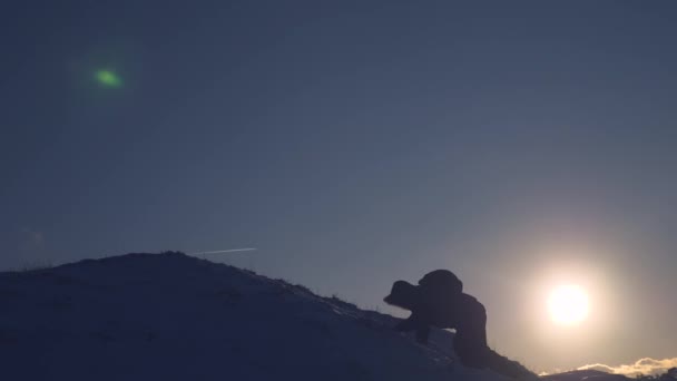 Klättrare klättrar snötäckta berg, glider ner och stiger igen i strålar ljusa solen. Turisten jublar över hans framgång, höjer händerna upp och lycklig hoppning. — Stockvideo