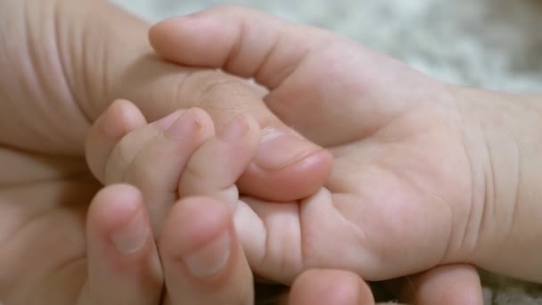 Mamá está cogida de la mano del pequeño bebé. Cuidado materno de niños pequeños. Primer plano — Vídeo de stock