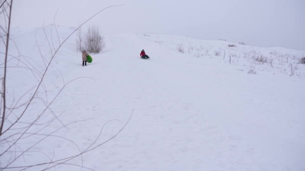 Счастливая девушка катится со снежной горы на снежной тарелке. Девушка идет на снежную гору, держа в руках снежную тарелку. — стоковое видео