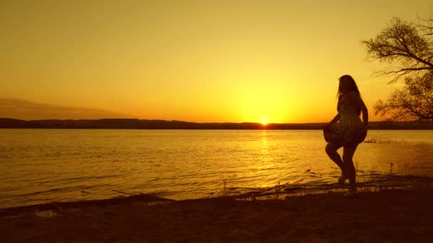 Νεαρό κορίτσι δωρεάν Χορεύοντας στο ηλιοβασίλεμα κόκκινο ήλιο στην παραλία. Ευτυχισμένη γυναίκα στην παραλία το βράδυ άλματος — Αρχείο Βίντεο