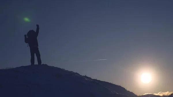 Grimpeur grimpe montagne enneigée, glisse vers le bas et se lève à nouveau dans les rayons du soleil. Le touriste se réjouit de son succès, lève les mains et saute heureux . — Photo