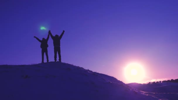 Men tourists with backpacks are in winter on hill in rays of bright sun. Climbers on top of a snowy mountain rejoice at their successes, raise their hands and happily jump. — Stock Video