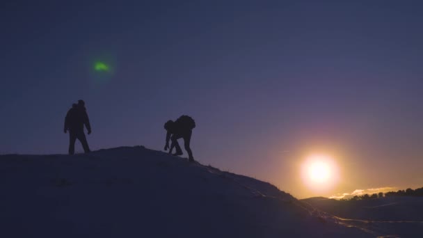 バックパックで男性観光客は美しい空と太陽の背景上に登る。雪に覆われた山の頂上に登山者が彼らの成功を喜ぶ彼らの手を上げるし、喜んでジャンプ. — ストック動画