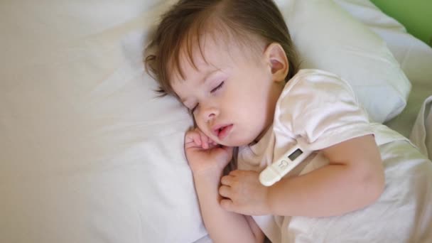 Chore dziecko z termometrem, spanie na białym łóżku. Temperatura dziecko jest mierzona za pomocą termometru w oddziale szpitala. — Wideo stockowe