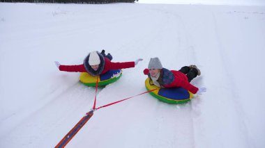 bir şişme kar tüp kışın halletme ve ellerini sallayarak mutlu çocuklar. çocuk gülmek ve sevinirler. Noel tatili için kış Parkta oynayan kız