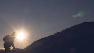 turist başına güzel gökyüzü arka plan üzerinde tırmanmaya yapar. Dağcı parlak güneş ışınlarının karlı dağda tırmanıyor. adam en üst başarısı için taşınır..