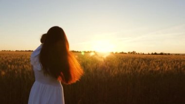 Genç Anne küçük kızıyla birlikte dans ve buğday, güzel bir gün batımı ışınlarının alanındaki gülüyor. Ağır çekim.