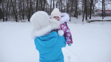 Anne, karlı bir yol yürüyüş küçük mutlu kızı kucağında taşır. Bebek ve anne bir kış yürüyüş. Çocuk gülümsüyor. Anne annelik bir çocukla bırak. Noel.