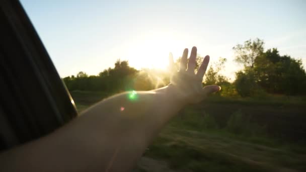 Girl rides in the car and waving her hand from the window and catches beautiful glare of the sun. Slow motion. — Stock Video