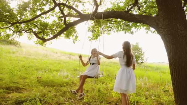 Girlfriends huśtawka na huśtawce pod drzewo lato dębu i śmiać się. Nastolatki dziewczyny grając razem w natura i smill. — Wideo stockowe