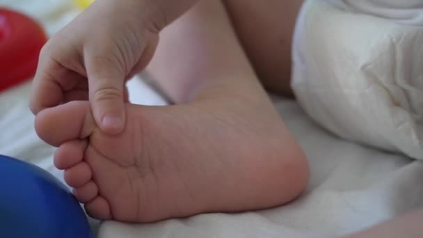 Lilla bebis leker med foten. Utveckling av barn i förskoleåldern. Närbild — Stockvideo